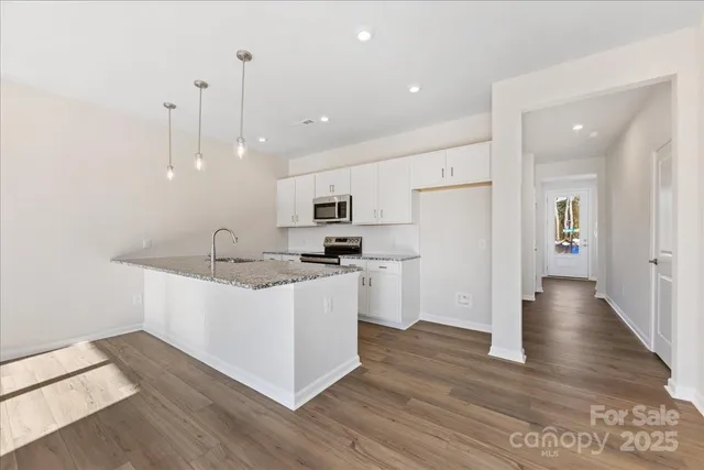 a kitchen with stainless steel appliances kitchen island a sink a refrigerator and a view of living room