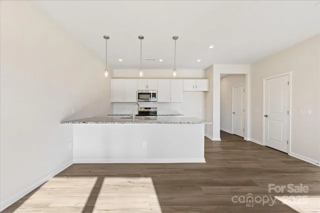 a view of kitchen with stainless steel appliances granite countertop cabinets and wooden floor
