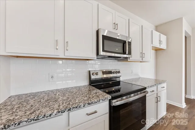 a kitchen with granite countertop white cabinets and a stove top oven