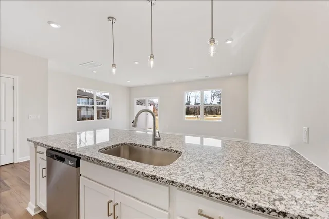 a kitchen with kitchen island granite countertop a sink and white cabinets
