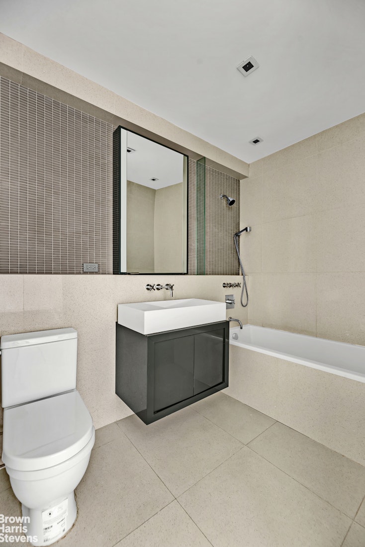 300 East 23rd Street, Unit 9B Manhattan, NY 10010 - Photo 7 of 14 a bathroom with a bathtub sink mirror and toilet