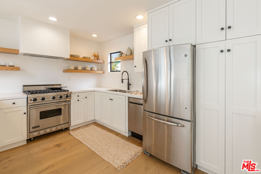 29233 Heathercliff Road, Unit 2 Malibu, CA 90265 - Photo 8 of 20 a kitchen with stainless steel appliances a refrigerator stove and white cabinets