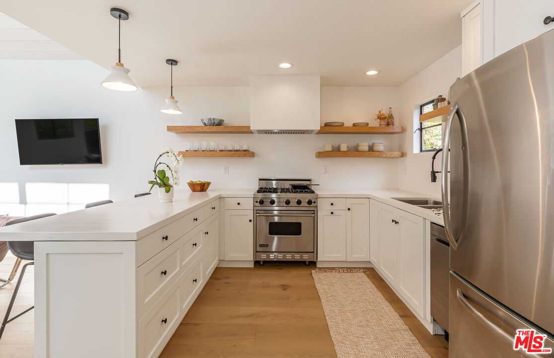 29233 Heathercliff Road, Unit 2 Malibu, CA 90265 - Photo 9 of 20 a kitchen with stainless steel appliances a refrigerator sink and wooden floor