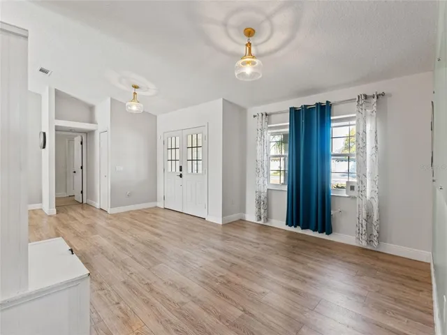 a view of an empty room with window and wooden floor
