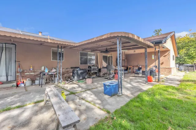 a view of a patio with table and chairs potted plants and a large tree