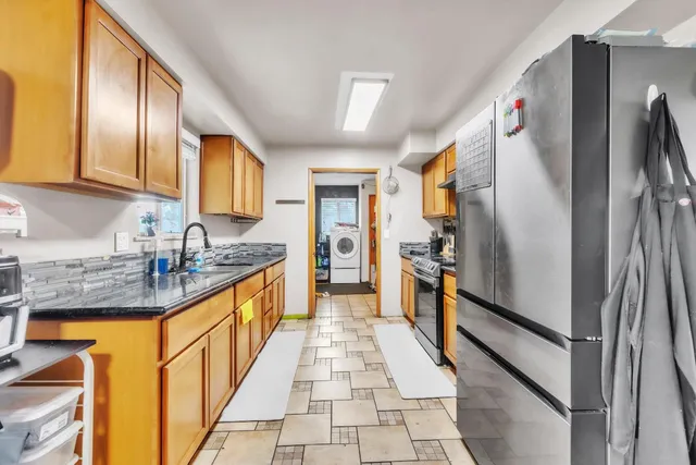 a large kitchen with stainless steel appliances granite countertop a refrigerator and a sink