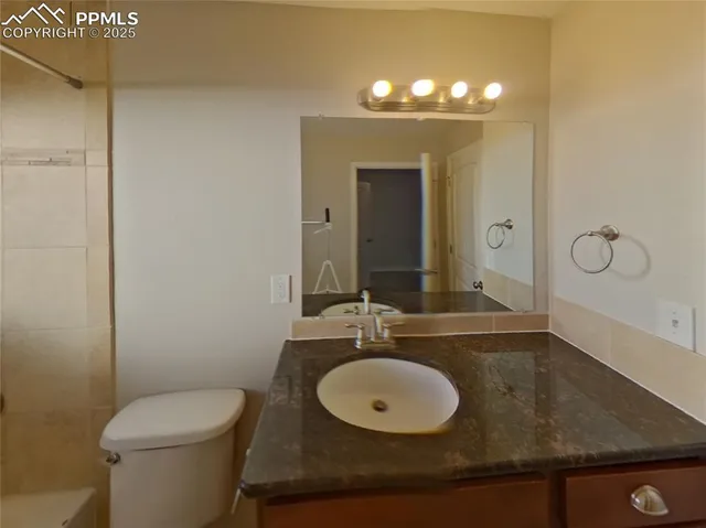 a bathroom with a granite countertop sink a toilet and a mirror
