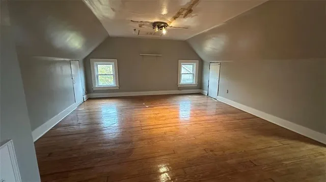 an empty room with wooden floor chandelier and windows