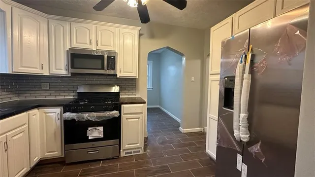 a kitchen with stainless steel appliances granite countertop a refrigerator a stove and a sink