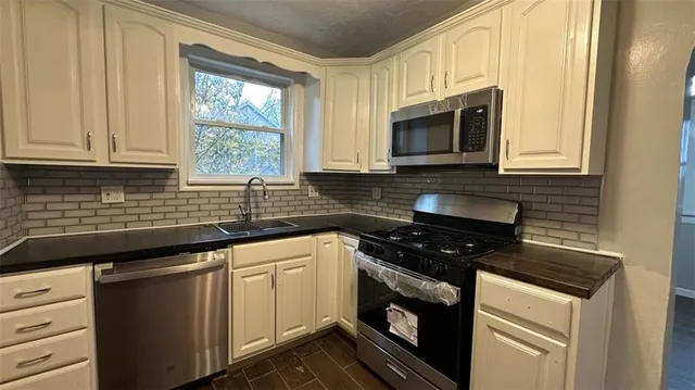 a kitchen with stainless steel appliances white cabinets granite counter tops and a window