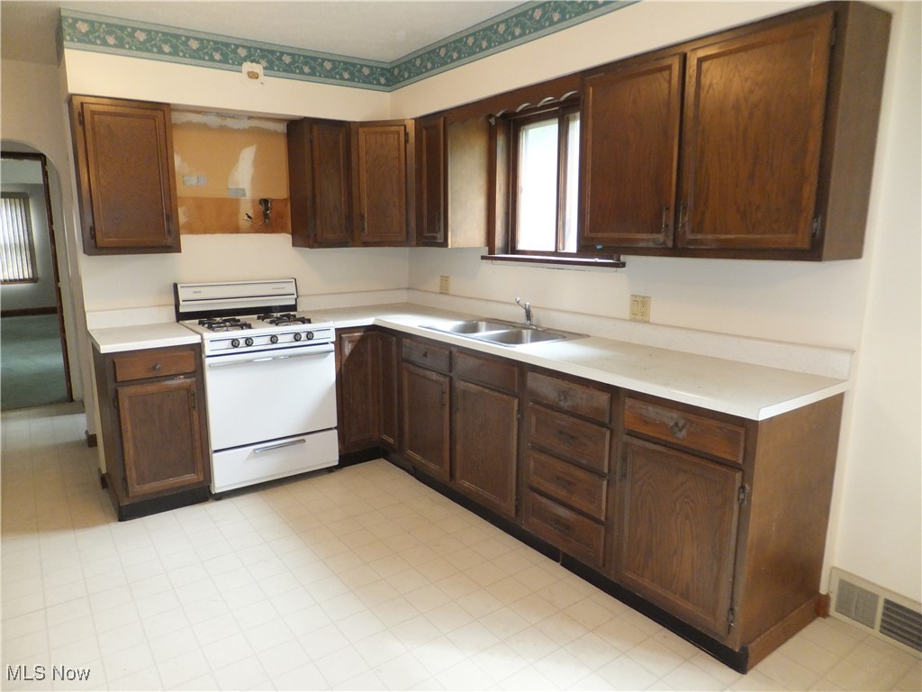 5113 Snow Road Cleveland, OH 44134 - Photo 22 of 40 Kitchen with dark brown cabinetry, white range with gas cooktop, and sink