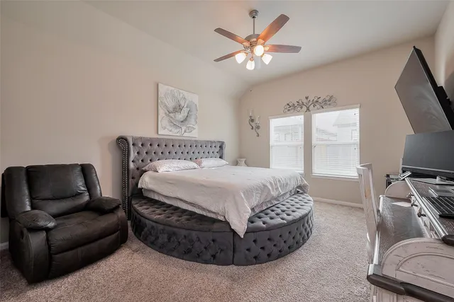 a spacious bedroom with a bed a couch and a flat tv screen on a dresser