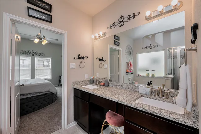 a en suite bathroom with a granite countertop double vanity sink and a mirror