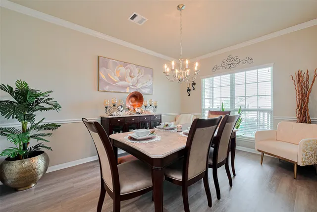 a view of a dining room with furniture a chandelier and wooden floor