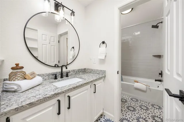 a bathroom with a granite countertop sink a mirror and a shower