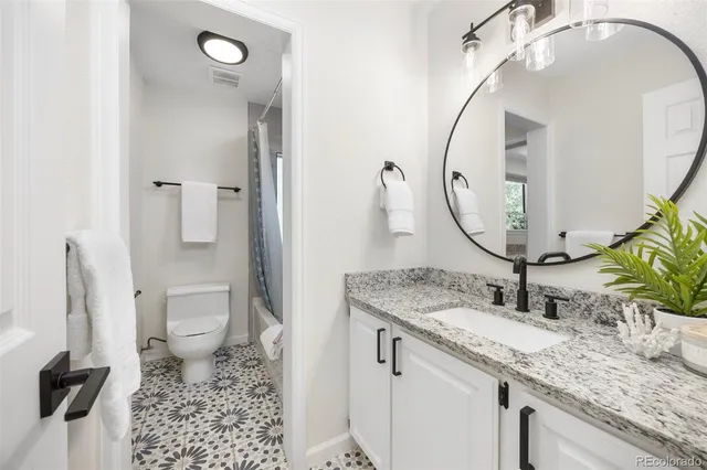 a bathroom with a granite countertop sink toilet and mirror