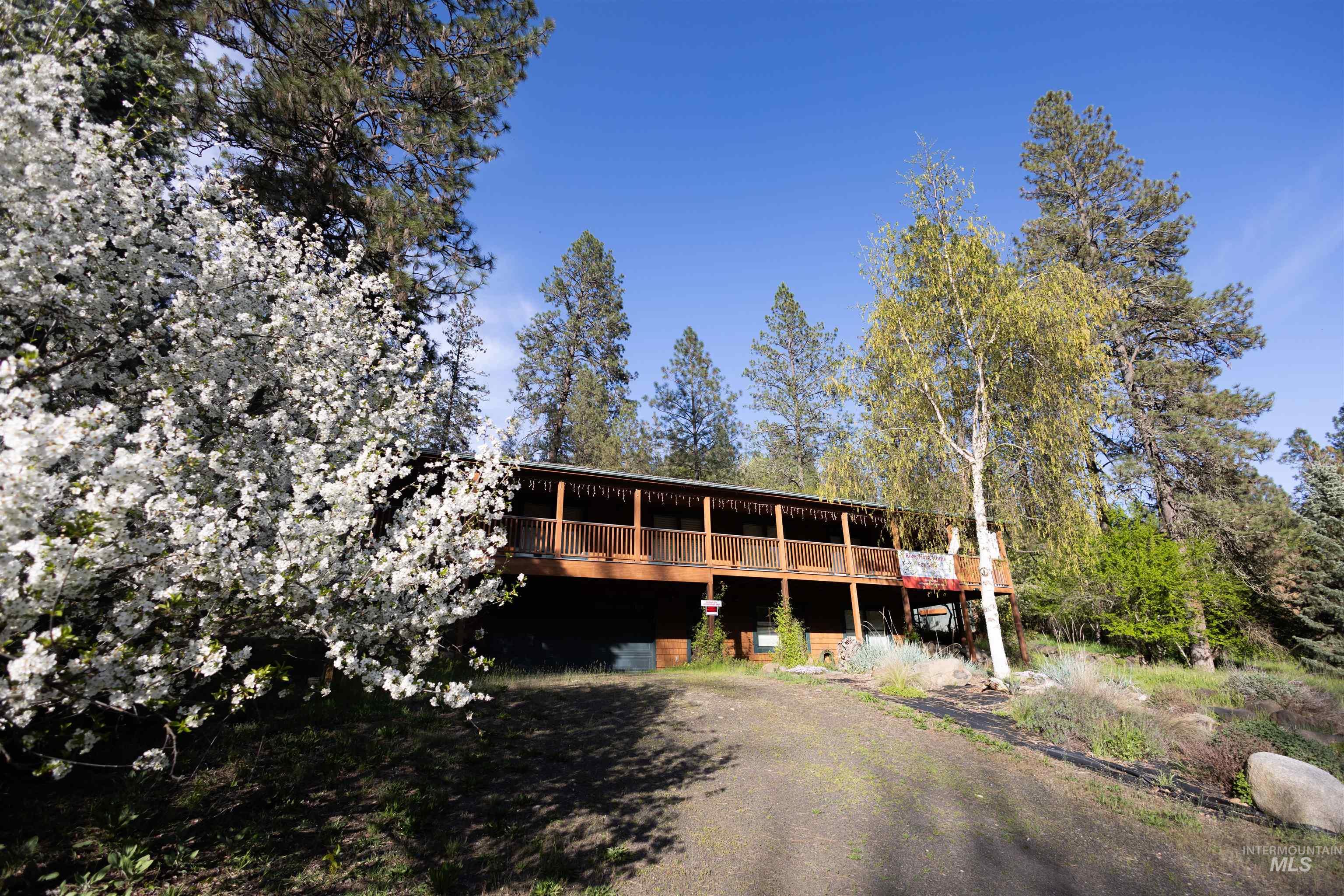 4480 Highway 12 Kamiah, ID 83536 - Photo 2 of 49 Multi-level dwelling featuring an expansive wood-plank deck with wood railings, surrounded by mature trees and natural landscaping