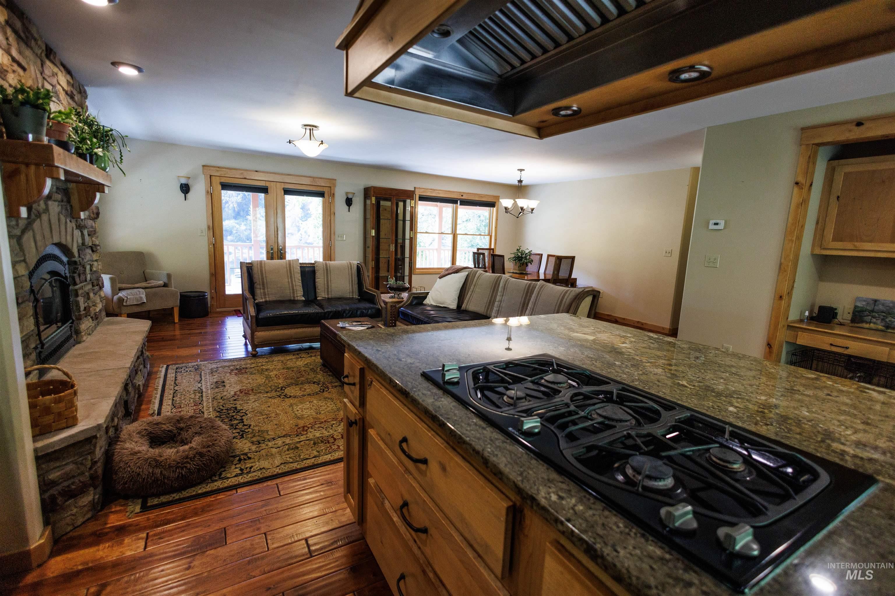 4480 Highway 12 Kamiah, ID 83536 - Photo 28 of 49 Kitchen featuring black gas cooktop, premium range hood, dark wood-type flooring, brown cabinets, and a stone fireplace