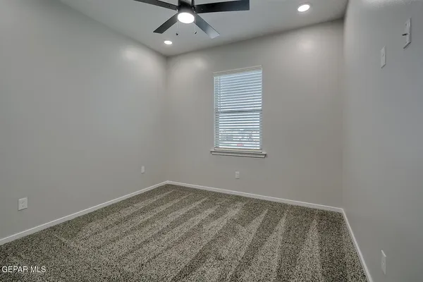 an empty room with a chandelier fan and windows
