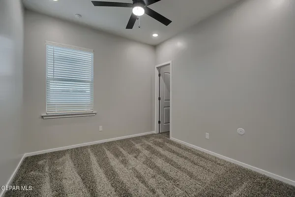 en empty room with windows and ceiling fan