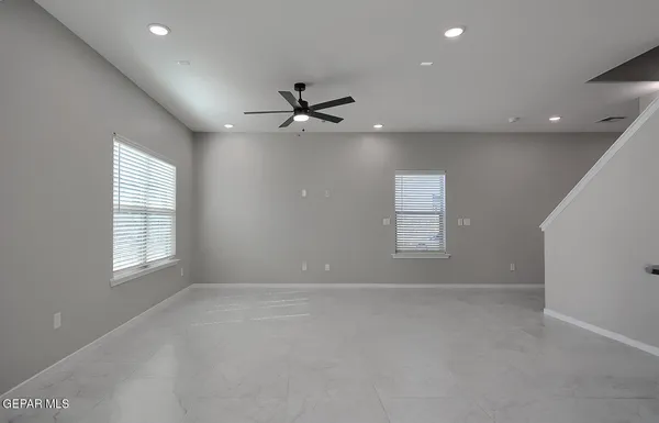 an empty room with windows and ceiling fan