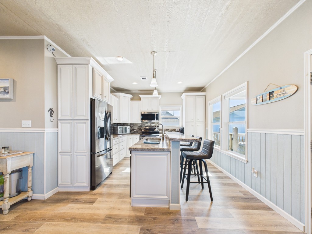 842 Main Street Crystal Beach, TX 77650 - Photo 28 of 45 a kitchen with stainless steel appliances kitchen island granite countertop a refrigerator a stove top oven and a dining table with wooden floor