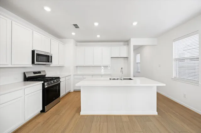 a kitchen with stainless steel appliances granite countertop a sink a stove top oven a counter space and cabinets