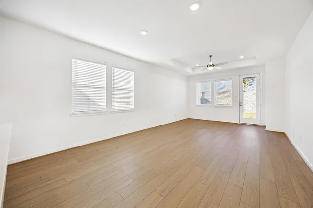 an empty room with wooden floor and windows