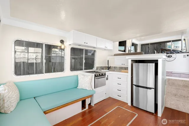 a living room with stainless steel appliances furniture and a kitchen view