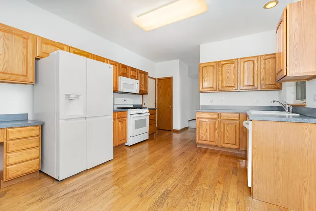 a kitchen with wooden floors and white appliances