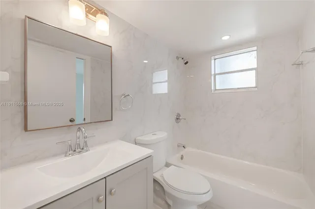 a bathroom with a bathtub shower sink vanity mirror and toilet