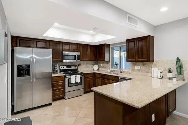 a kitchen with stainless steel appliances granite countertop a sink stove microwave and refrigerator