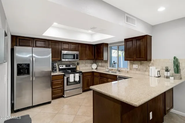 a kitchen with stainless steel appliances granite countertop a sink stove microwave and refrigerator