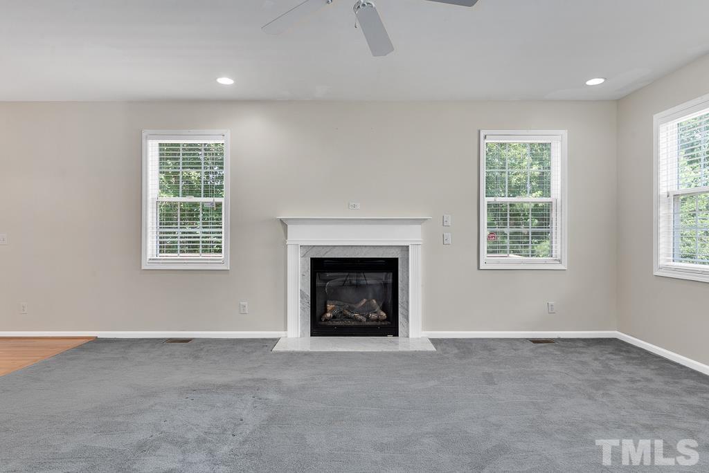 110 Castlebar Lane Durham, NC 27713 - Photo 13 of 32 an empty room with a fireplace and windows