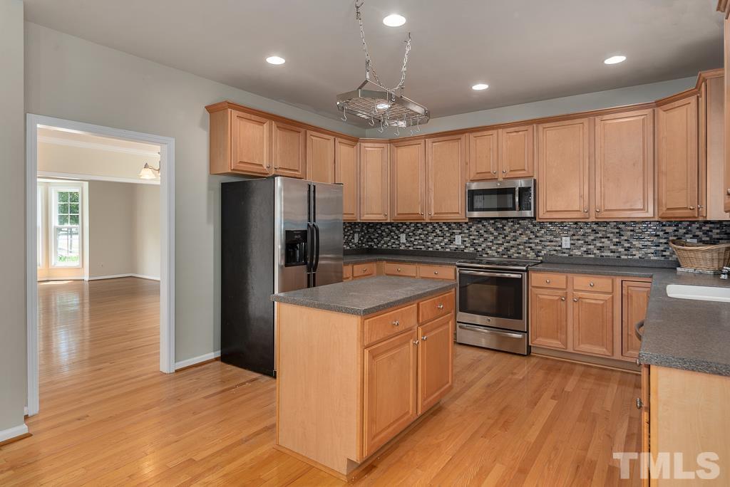 110 Castlebar Lane Durham, NC 27713 - Photo 8 of 32 a kitchen with kitchen island granite countertop wooden cabinets and a stove