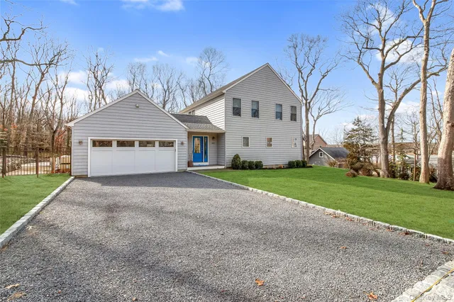a view of a white house with a yard and large trees