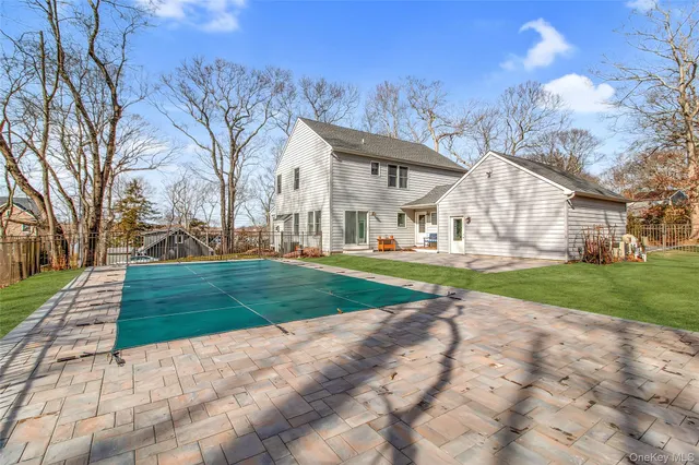 a view of a white house with a big yard plants and large trees
