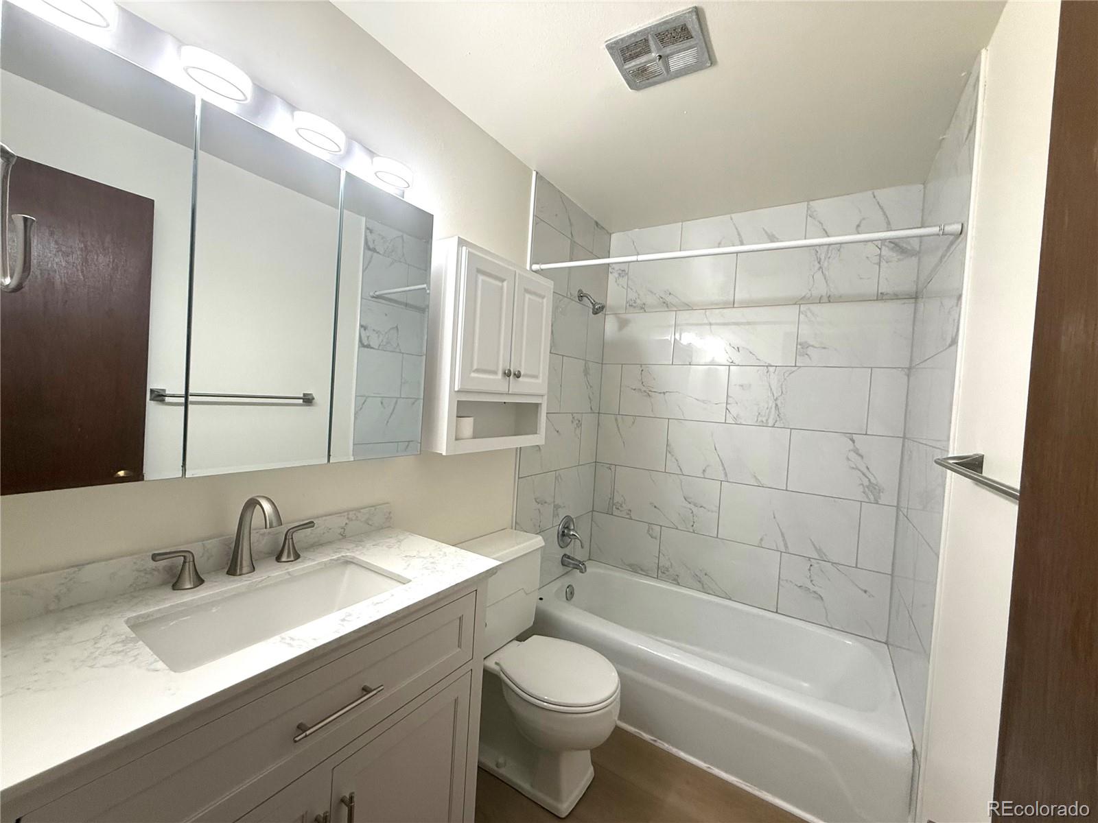 6155 Simms Street, Unit 2 Arvada, CO 80004 - Photo 5 of 7 a bathroom with a shower sink vanity mirror and toilet