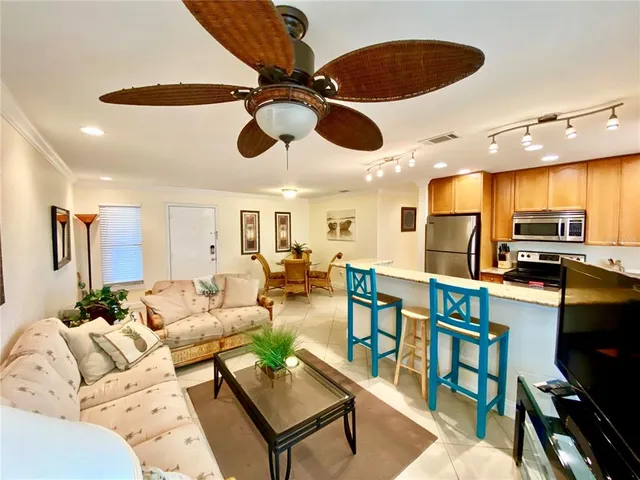 a living room with furniture kitchen view and a wooden floor