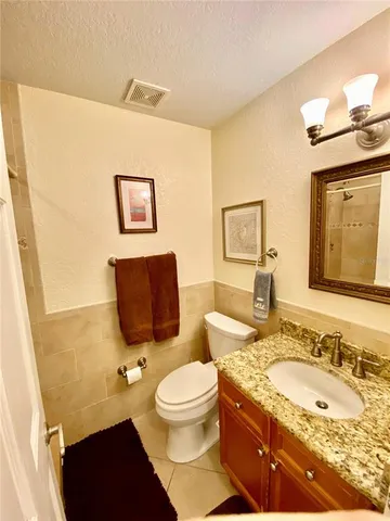 a bathroom with a granite countertop toilet sink and mirror