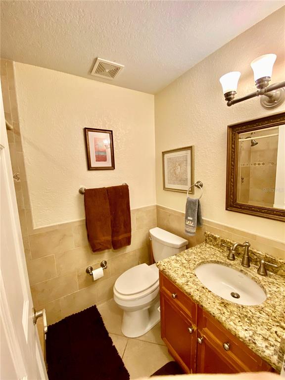 9060 Blind Pass Road, Unit 25 St. Pete Beach, FL 33706 - Photo 9 of 25 a bathroom with a granite countertop toilet sink and mirror