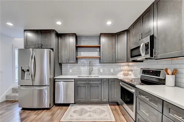a kitchen with stainless steel appliances granite countertop a refrigerator a sink dishwasher a stove and a microwave oven on granite countertops