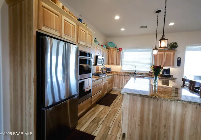 a kitchen with stainless steel appliances granite countertop a table chairs and a refrigerator