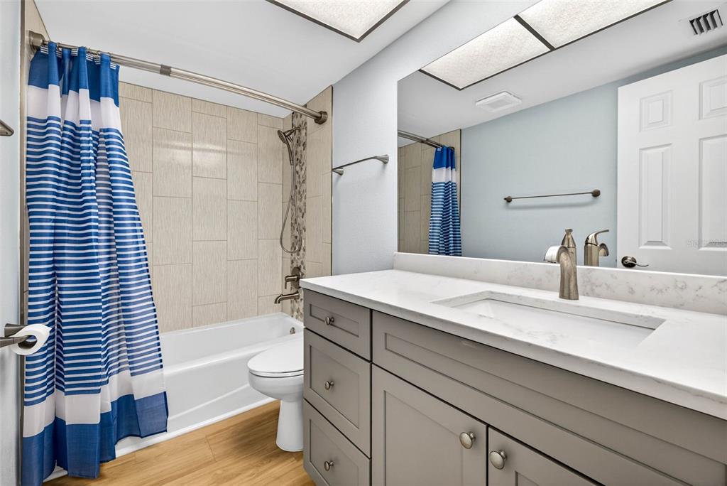 5197 Silent Loop, Unit 124 New Port Richey, FL 34652 - Photo 28 of 55 a bathroom with a granite countertop sink toilet and shower