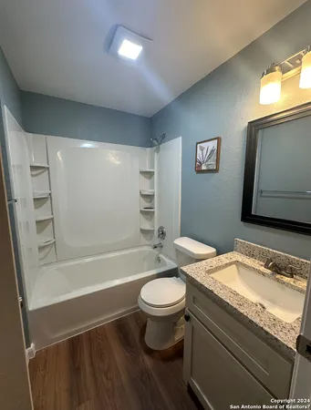 a bathroom with a granite countertop sink toilet a mirror and bathtub