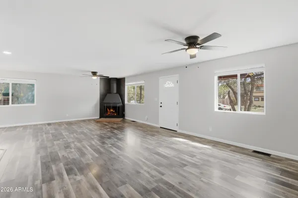 a view of empty room with wooden floor and fan