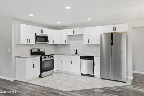 a kitchen with granite countertop a refrigerator stove top oven and sink