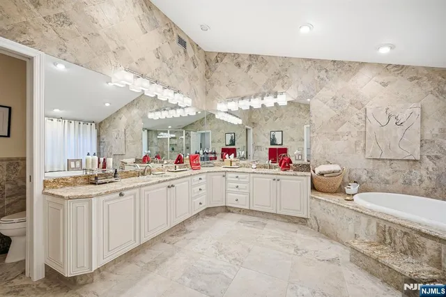a large white bathroom with a sink mirror and bathtub