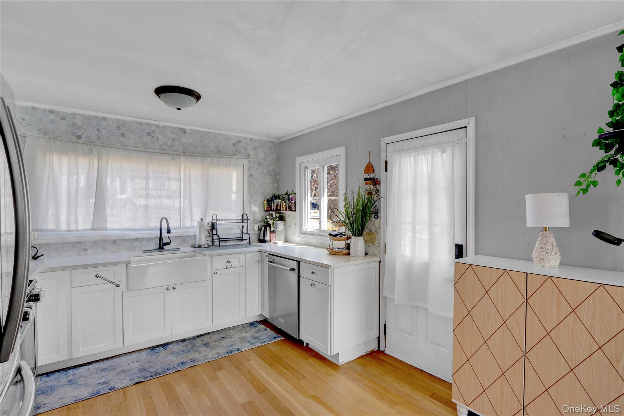 243 Lakeside Trail Ridge, NY 11961 - Photo 11 of 38 a kitchen with white cabinets a sink potted plant and a window