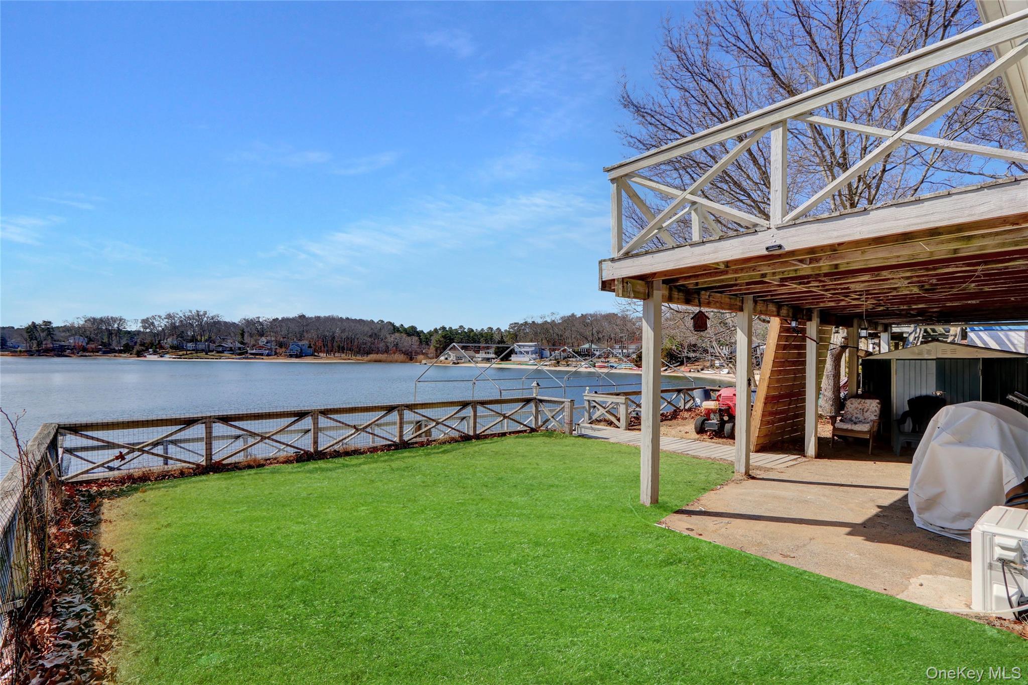 243 Lakeside Trail Ridge, NY 11961 - Photo 26 of 38 a view of a chair and tables in the patio near a lake
